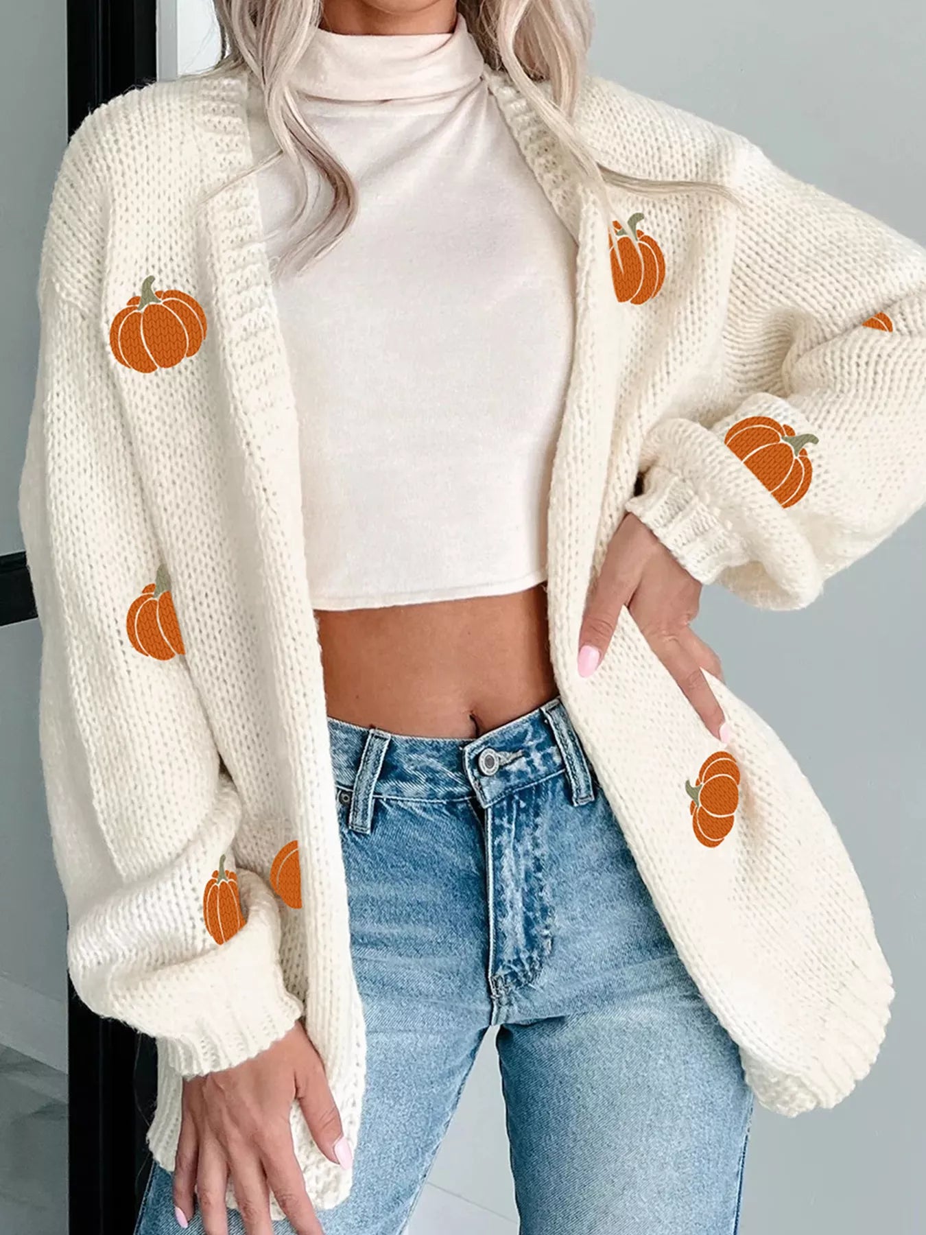 White knit cardigan with embroidered pumpkins styled with denim