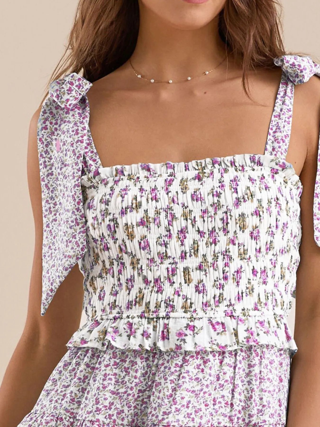 Smocked purple floral top with ruffle detail and bow tie straps.