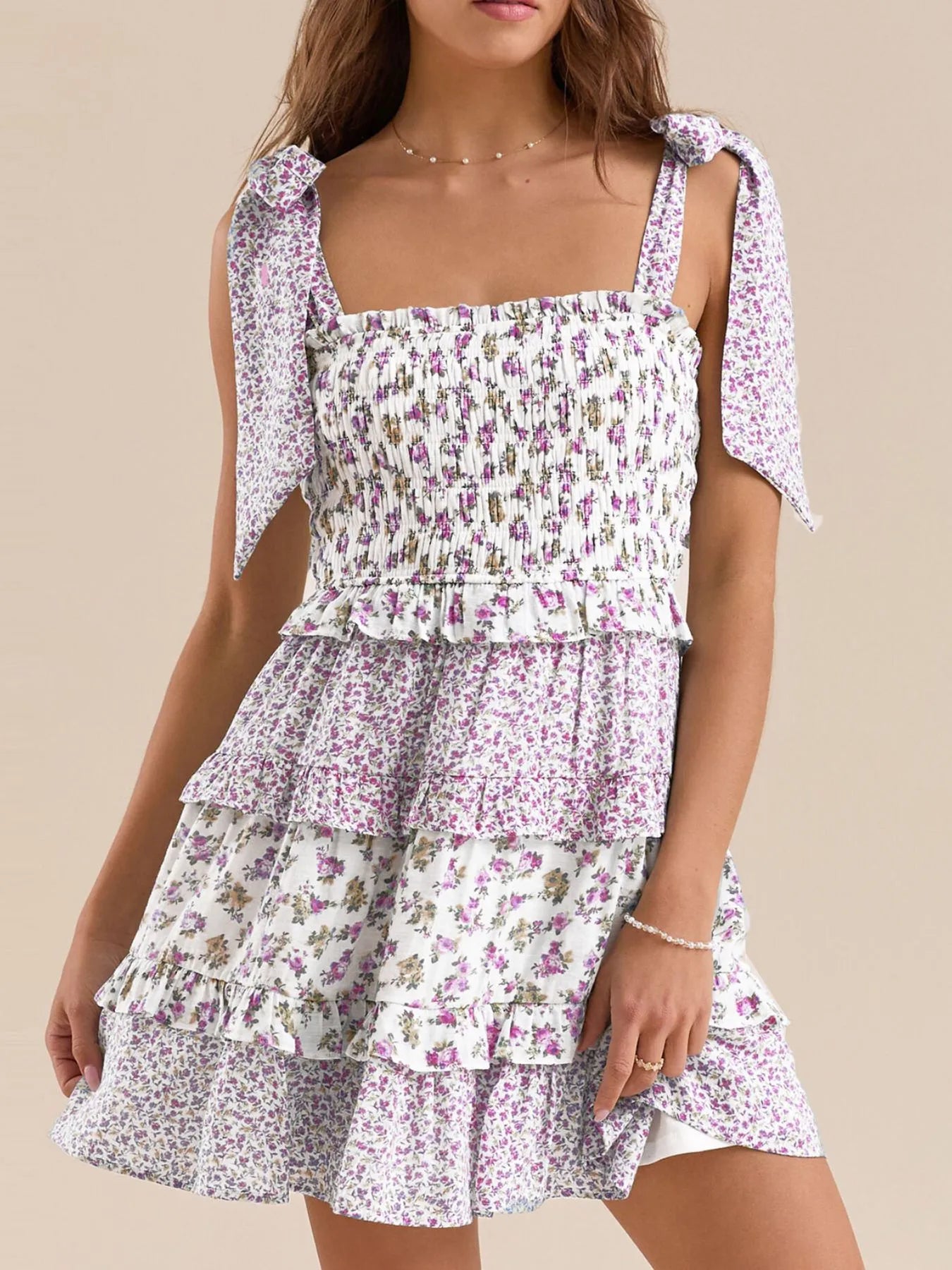 Purple floral smocked dress with tie shoulder straps and tiered ruffle layers.