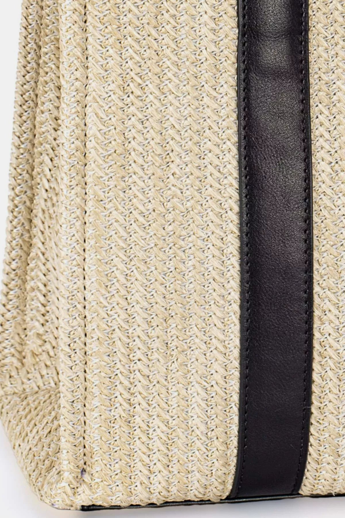 Close up view showing detailed woven handbag with black trim and straps
