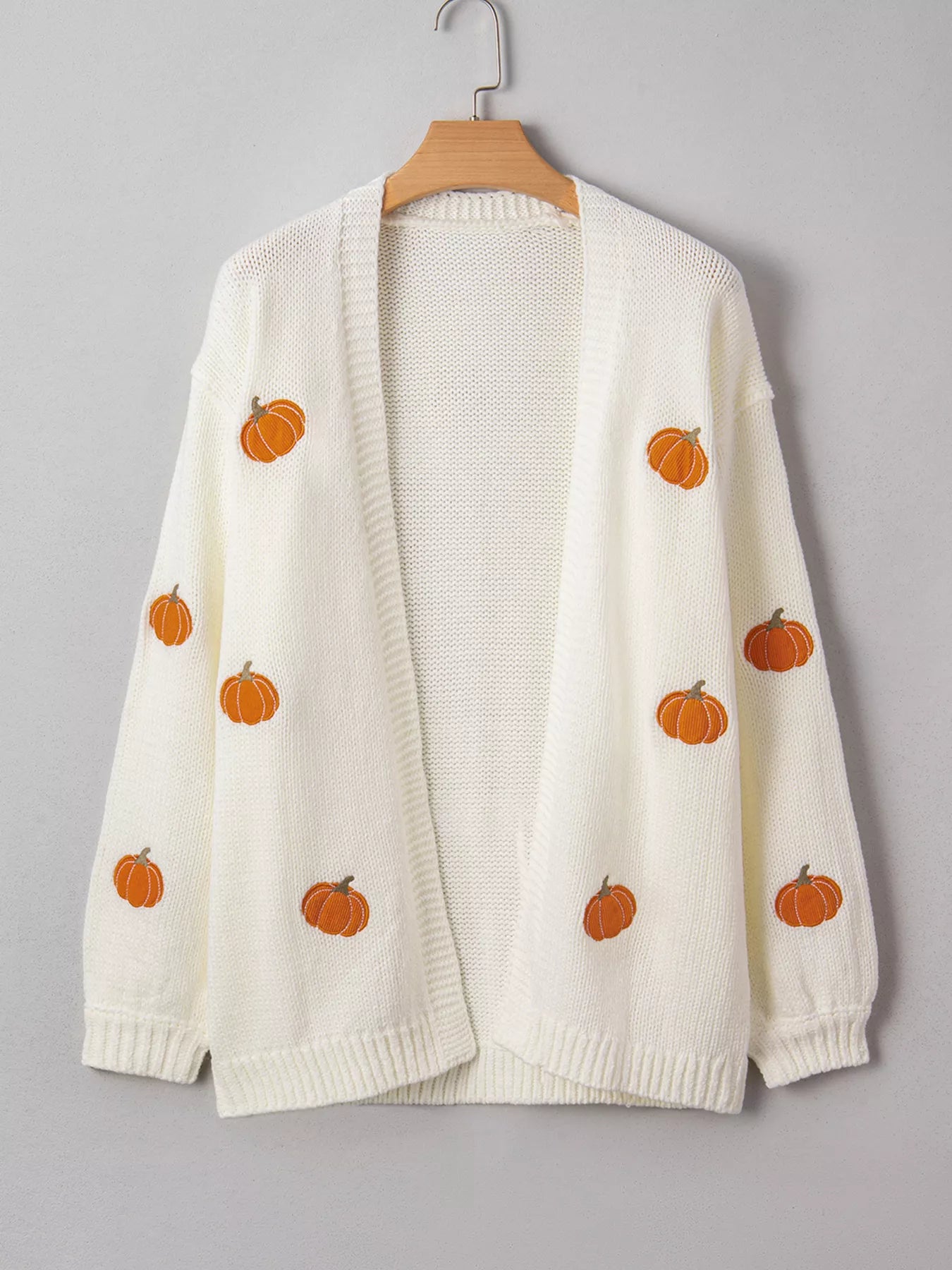 White pumpkin knit cardigan displayed on hanger for detail