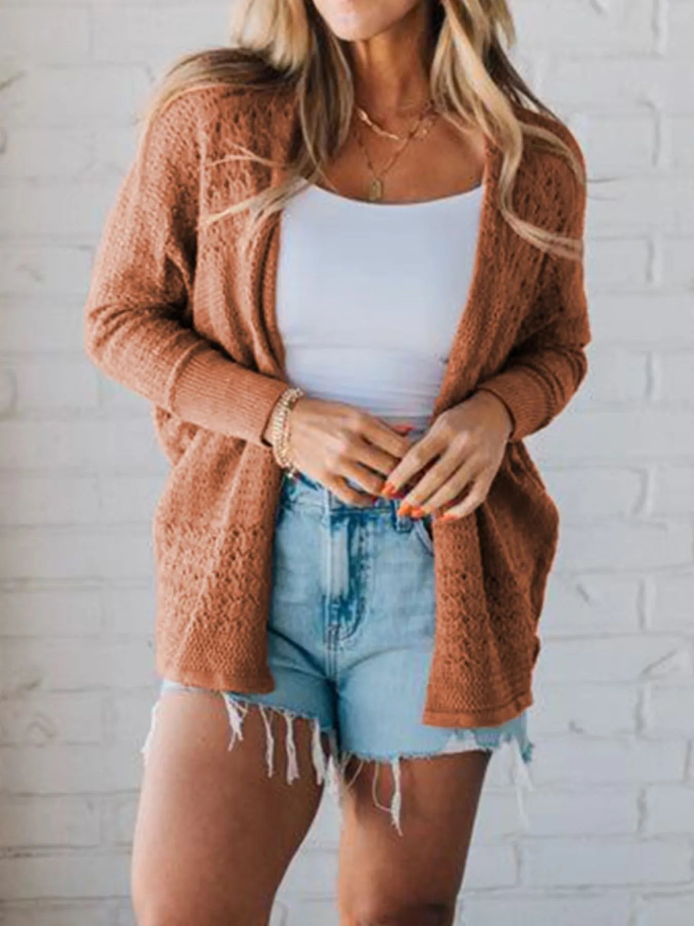 Front view of brown cardigan layered over white tank and denim