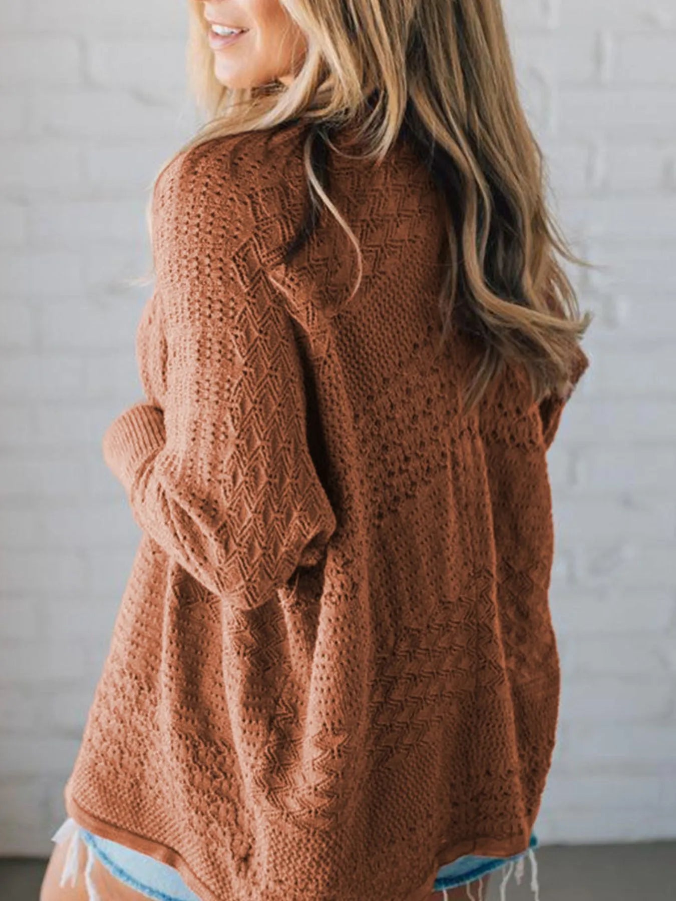 Back view of brown knitted cardigan with long sleeves and textured design